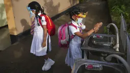 Para siswa sekolah dasar mencuci tangan sebelum memasuki ruang kelas di sebuah sekolah di Kolombo, Sri Lanka, 25 Oktober 2021. Sri Lanka memulai kembali semua sekolah dasar yang telah ditutup lebih dari enam bulan karena pandemi COVID-19. (AP Photo/Eranga Jayawardena)