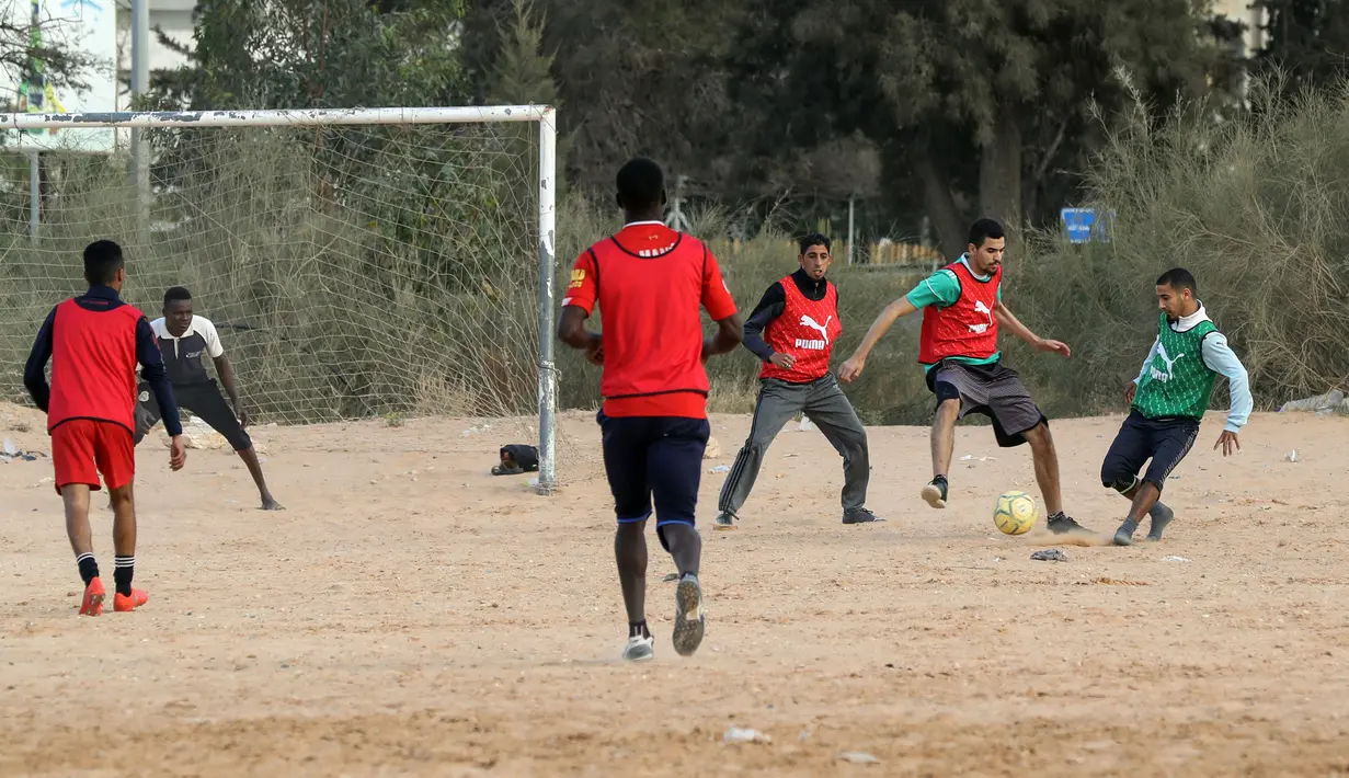Sejumlah pria bermain sepak bola di lapangan tanah sebelum buka puasa selama bulan Ramadhan, di ibu kota Libya, Tripoli (24/4/2021). (AFP/Mahmud Turkia)