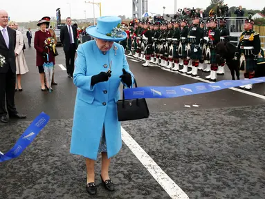 Ratu Inggris Elizabeth II memotong pita dalam peresmian jembatan Queensferry di Skotlandia, Minggu (4/9). Jembatan Queensferry resmi dibuka untuk menghubungkan antar ibu kota Edinburgh dengan bagian utara Skotlandia. (Andrew Milligan/PA via AP)