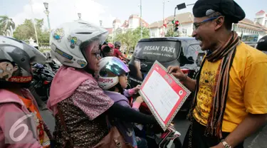 Komunitas Gerakan Literasi Aksara Jawa membagikan kalender berhuruf Jawa kepada  pengunjung  pada peringatan Hari Aksara Internasional ke-50 di Titik Nol km, Yogyakarta, Kamis (8/9). (Liputan6.com/ Boy Harjanto)