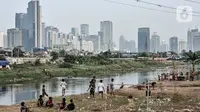 Anak-anak bermain di bantaran Kanal Banjir Barat dengan latar belakang gedung pencakar langit di Jakarta, Kamis (6/8/2020). Badan Pusat Statistik mencatat pertumbuhan ekonomi Indonesia Kuartal II/2020 minus 5,32 persen akibat perlambatan sejak adanya pandemi COVID-19. (merdeka.com/Iqbal S. Nugroho)