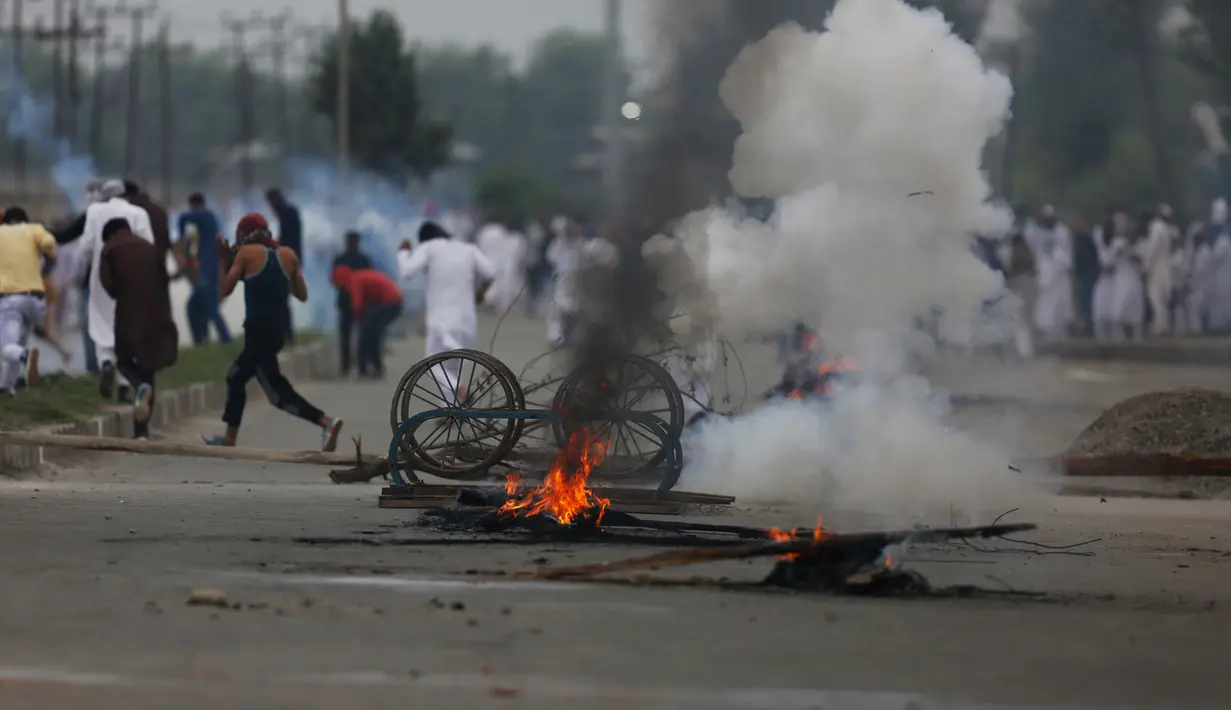 Para pengunjuk rasa membakar gerobak untuk memblokade jalan usai melakukan salat Idul Fitri di Srinagar, India (26/6). Mereka memprotes peraturan di India dan pro-kemerdekaan Kashmir. (AP Photo / Mukhtar Khan)