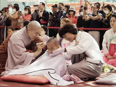 Seorang biksu mencukur rambut anak laki-laki dalam sebuah acara kebaktitan di Kuil Jogye di Seoul, Korea Selatan, Selasa, 9 Mei 2023. (AP Photo/Ahn Young-joon)