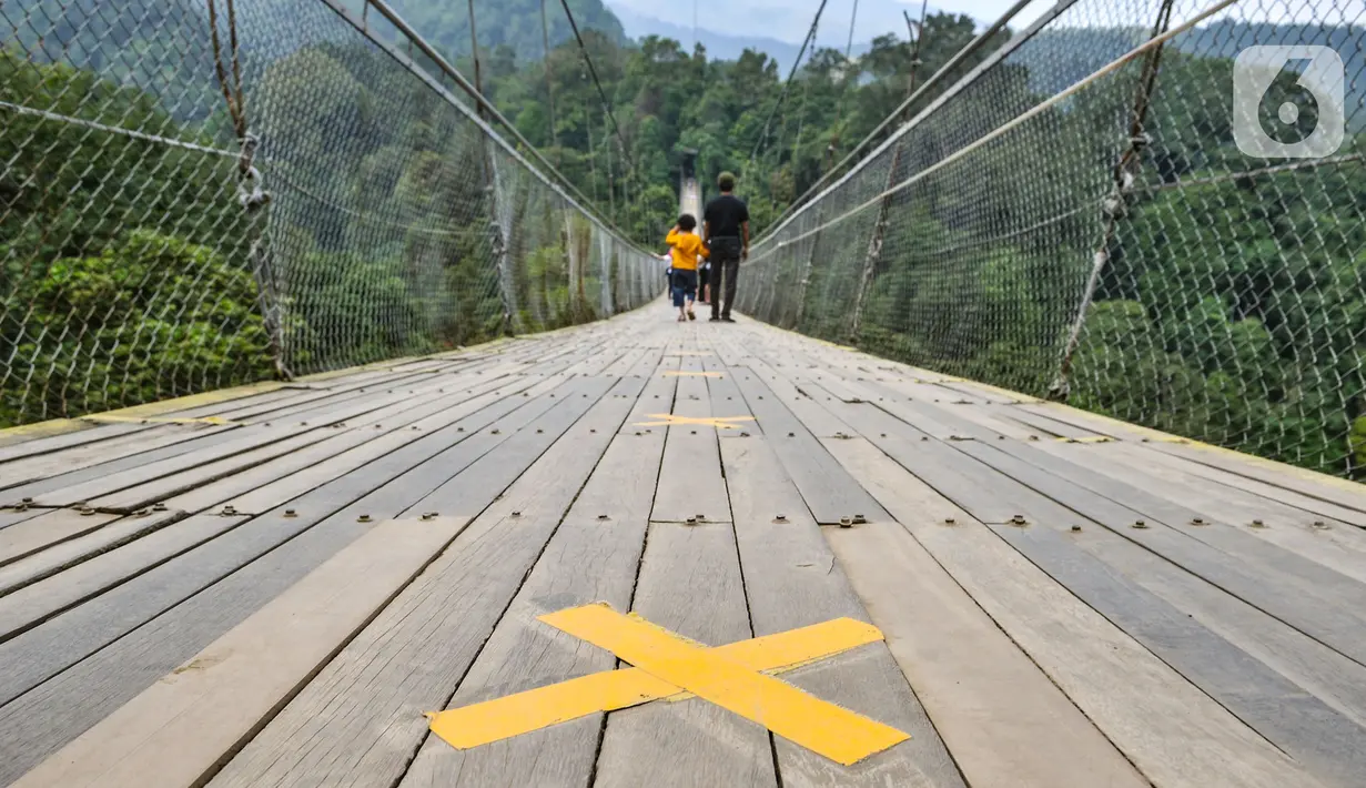 Tanda jaga jarak terpasang di lantai Jembatan Gantung Situ Gunung, Sukabumi, Jawa Barat, Minggu (20/9/2020). Dari rata-rata 2.500 pengunjung tiap harinya kini hanya di bawah 1.000 pelancong per hari akibat merebaknya pandemi Covid-19 serta adanya penerapan PSBB. (merdeka.com/Iqbal S. Nugroho)