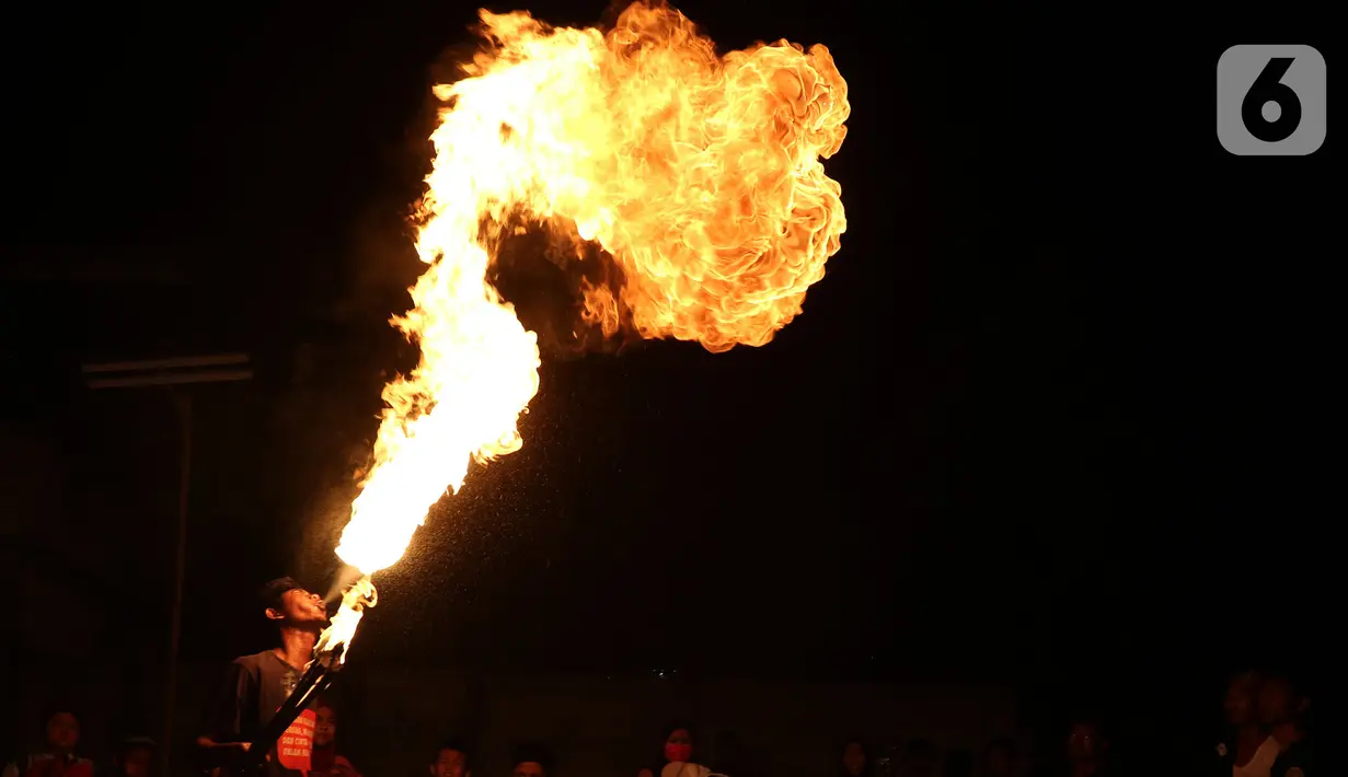 Seorang warga beraksi memainkan api selama pawai obor di Kawasan Rempoa, Tangerang Selatan, Rabu (19/08/2020). Pawai obor tersebut dilakukan dalam rangka menyambut peringatan tahun baru Islam 1 Muharram 1442 H. (Liputan6.com/Herman Zakharia)