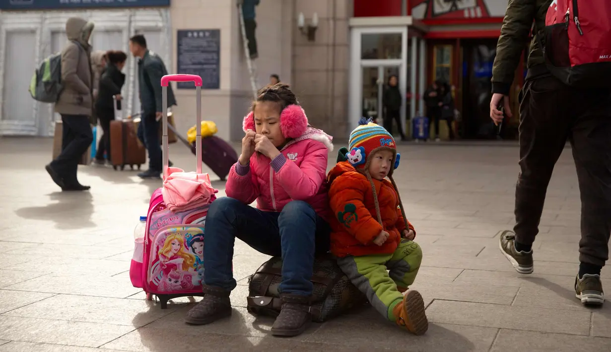 Anak-anak duduk di barang bawaannya di luar Stasiun Kereta Api Beijing, China (9/2). Sambut perayaan Imlek 2018, Jutaan warga China mulai memenuhi stasiun, bandara dan jalan yang diperkirakan akan dimulai akhir pekan ini. (AP Photo / Mark Schiefelbein)