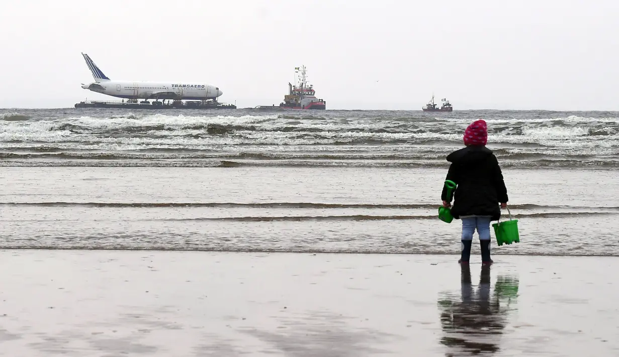 Seorang gadis mengamati Boeing 767 yang ditarik dari bandara Shannon ke laut di sekitar pantai barat Irlandia, Sabtu (7/5). Pekerja menghabiskan enam jam untuk memuat pesawat ke dalam tongkang yang akan berlayar ke arah utara. (REUTERS/Clodagh Kilcoyne)