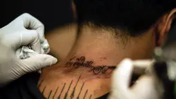 Seorang pria mentato bagian lehernya untuk menghormati Raja Bhumibol Adulyadej di Bangkok, Thailand, Selasa (18/10). Tato tersebut berbunyi "Saya lahir pada masa pemerintahan Raja Rama IX". (REUTERS / Athit Perawongmetha)