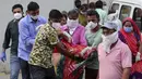 Kerabat membawa seorang perempuan yang pingsan setelah melihat tubuh suaminya di rumah sakit pemerintah khusus COVID-19 di Ahmedabad, India, Selasa (27/4/2021). Kasus virus corona di India melonjak lebih cepat dari tempat lain di dunia. (AP Photo/Ajit Solanki)