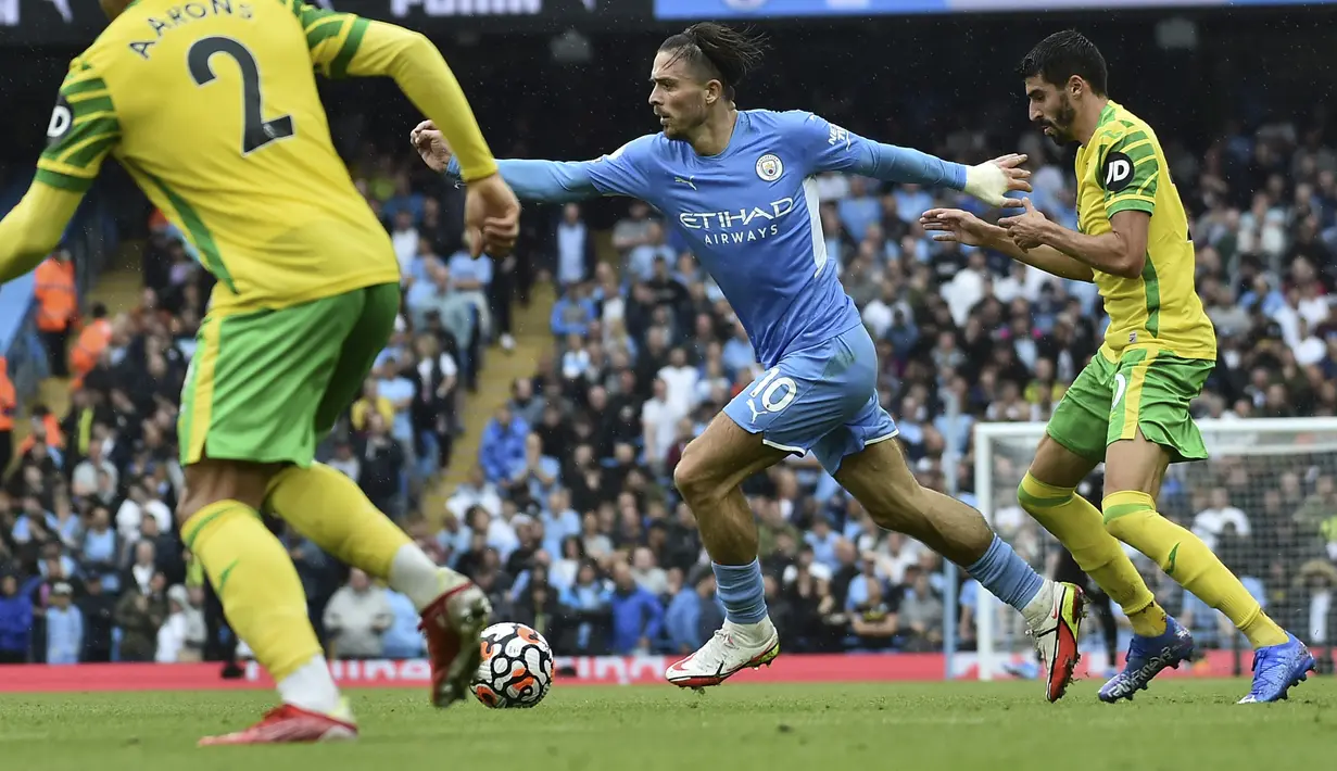 Gelandang Manchester City, Jack Grealish membawa bola dari kawalan pemain Norwich City, Pierre Lees-Melou pada pertandingan pekan kedua Liga Inggris di stadion Etihad di Manchester, Inggris, Sabtu (21/8/2021). Man City menang telak atas Norwich City 5-0. (AP Photo/Rui Vieira)