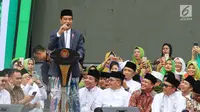 Presiden Joko Widodo atau Jokowi memberi sambutan dalam Harlah ke-73 Muslimat NU di SUGBK, Jakarta, Minggu (27/1). Jokowi datang dengan mengenakan kain sarung, jas, dan kopiah hitam. (Liputan6.com/Johan Tallo)