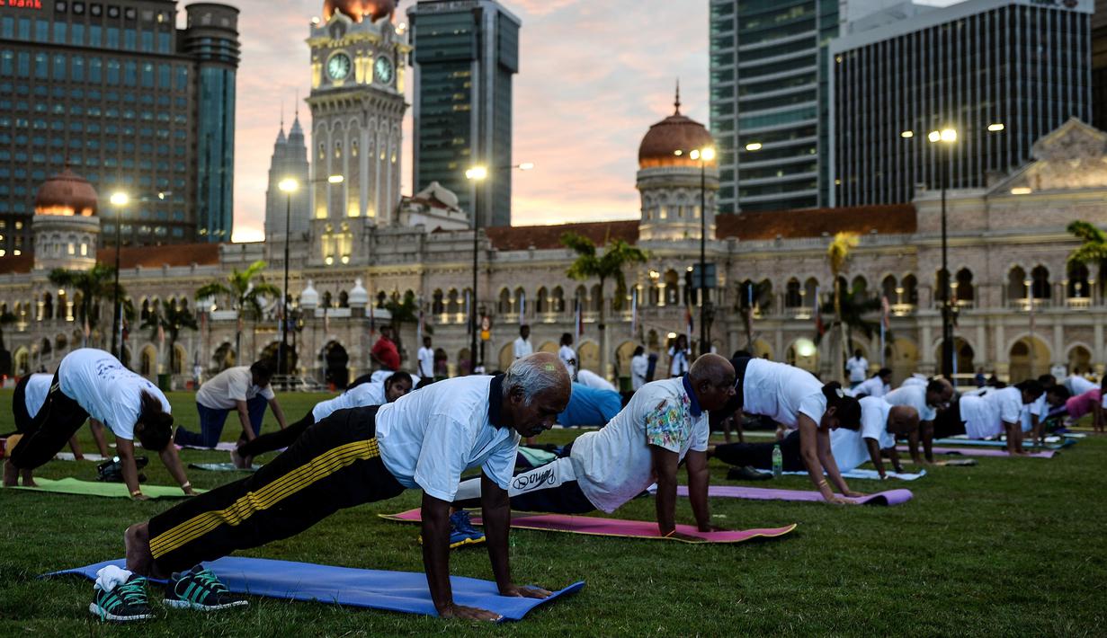  Sejumlah orang melakukan gerakan yoga di ikon bangunan Sultan Abdul Samad, Kuala Lumpur, Malaysia, (21/6). Sejumlah negara di dunia sedang merayakan Hari Yoga Dunia yang jatuh pada tanggal 21 Juni. (MANAN VATSYAYANA / AFP)