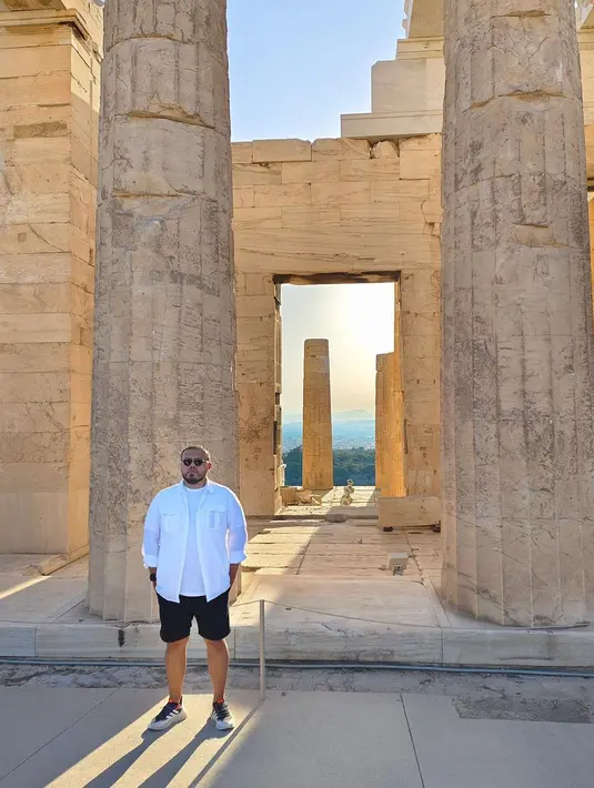 Pemberhentian Joko Anwar berikutnya, Athena Yunani. Mengenakan baju serbaputih yang dipadukan celana hitam pendek, sneakers, dan kacamata, ia berdiri di salah satu spot ikonis Yunani yakni kawasan Akropolis, Athena. Tak perlu dilapisi filter, panorama Yunani sudah keren dari sononya. Pose berdiri di antara dua pilar ini layak disontek, ya. (Foto: Dok. Instagram @jokoanwar)