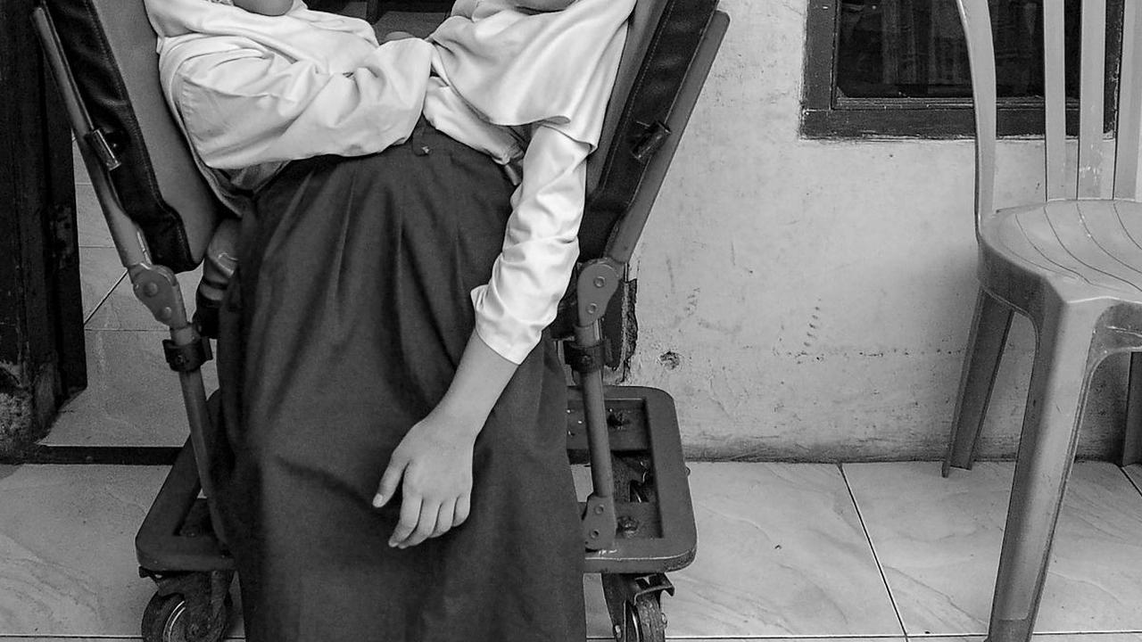 Anak kembar siam Al Dewi Putri Ningsih (9) dan Al Putri Anugrah (9) menggunakan kursi roda khusus ketika bersiap berangkat ke sekolah di Garut, Jawa Barat, dalam foto yang diambil pada 22 Mei 2023. Al Dewi dan Al Putri terlahir dalam kondisi kembar siam d