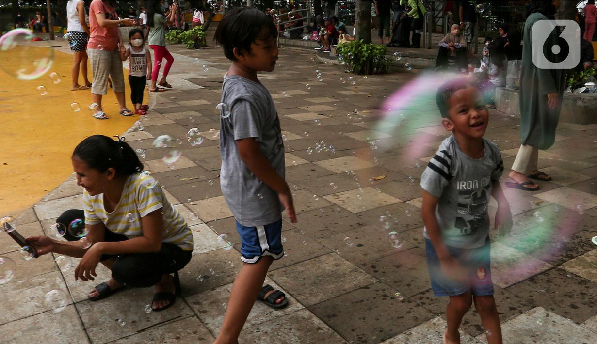 Anak-anak bermain gelembung sabun saat menghabiskan waktu di Taman Puring, Jakarta, Minggu (9/1/2022). Di tengah ancaman penyebaran covid-19 varian Omicron dan pemberlakukan PPKM level 2, masyarakat tetap melakukan aktivitas pada akhir pekan di luar rumah. (Liputan6.com/Johan Tallo)