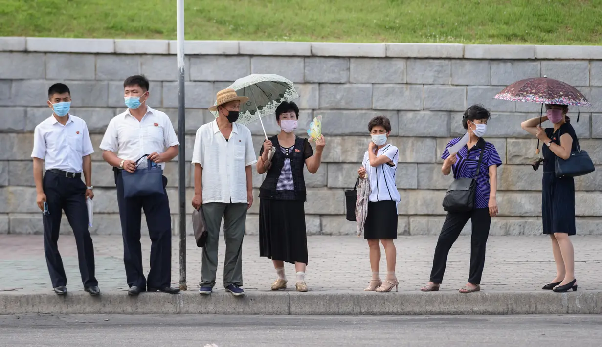 Komuter menunggu bus saat suhu tinggi mencapai 34 derajat celsius di Pyongyang, Korea Utara, Rabu (21/7/2021). Musim Panas dimulai pada bulan Juni hingga Agustus, dan puncak musim panas adalah bulan Agustus. (KIM Won Jin / AFP)