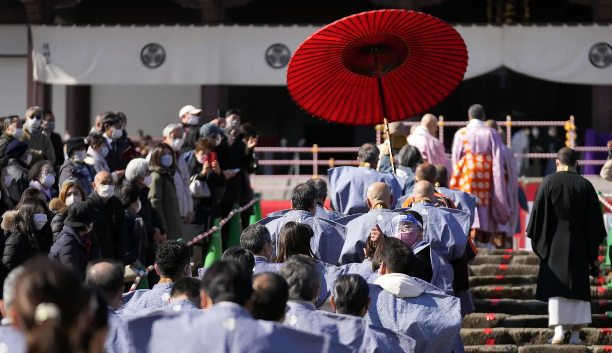 Para pelempar kacang berjalan sebelum "Mame-maki," upacara pelemparan kacang, di kuil Buddha Zojoji di Tokyo, 3 Februari 2022. Ritual yang diyakini membawa keberuntungan dan mengusir kejahatan dilakukan setiap tahun untuk menandai awal musim semi dalam kalender lunar. (AP Photo/Eugene Hoshiko)
