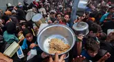 Warga Palestina berkumpul untuk menerima makanan hangat di titik distribusi makanan di kamp Nuseirat, Jalur Gaza Tengah pada 21 Mei 2025. (Eyad BABA/AFP)