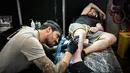 Seorang pria membuat tato saat Paris Tattoo Convention di Grand Halle de la Villette, Paris, Prancis, Jumat (9/3). Paris Tattoo Convention berlangsung dari tanggal 9 sampai 11 Maret. (Philippe LOPEZ/AFP)