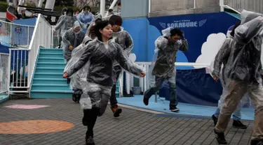 Sejumlah peserta memakai mantel plastik saat mengikuti simulasi evakuasi anti-rudal di taman hiburan Tokyo Dome City, Jepang, (22/1). Di tengah balistik Korea Utara, warga Jepang menggelar simulasi evakuasi anti-rudal. (AFP Photo/Toshifumi Kitamura)