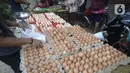 Pedagang telur melayani pembeli di pinggir jalan kasawan Perumahan Nusa Indah, Tangerang Selatan, Banten, Jumat (22/5/2020). Harga telur warna cokelat Rp 22 ribu per kilogram, sedangkan telur warna putih Rp 20 ribu per kilogram. (merdeka.com/Dwi Narwoko)