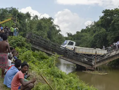 Penduduk desa berkumpul di dekat jembatan yang roboh di desa Phasidewa dekat perbatasan India-Bangladesh di pinggiran Siliguri di negara bagian India, Bengal Barat (7/9). Tidak ada korban dalam kejadian jembatan roboh tersebut. (AFP Photo/Diptendu Dutta)