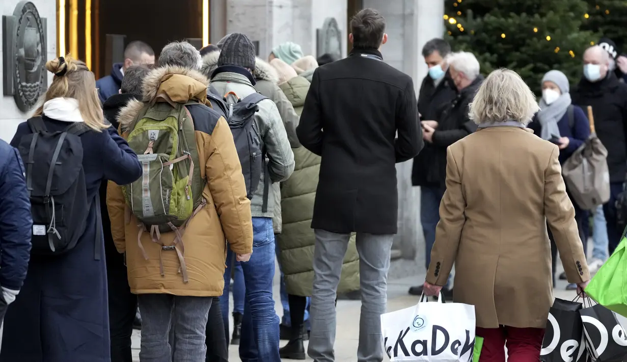 Orang-orang menunjukkan status vaksinasi mereka saat antre di depan department store terkenal 'KaDeWe' (Department Store Of The West) di Berlin, Selasa (21/12/2021). Jerman akan memperkenalkan langkah-langkah baru untuk mengekang penyebaran COVID-19 sebelum Malam Tahun Baru. (AP Photo/Michael Sohn)