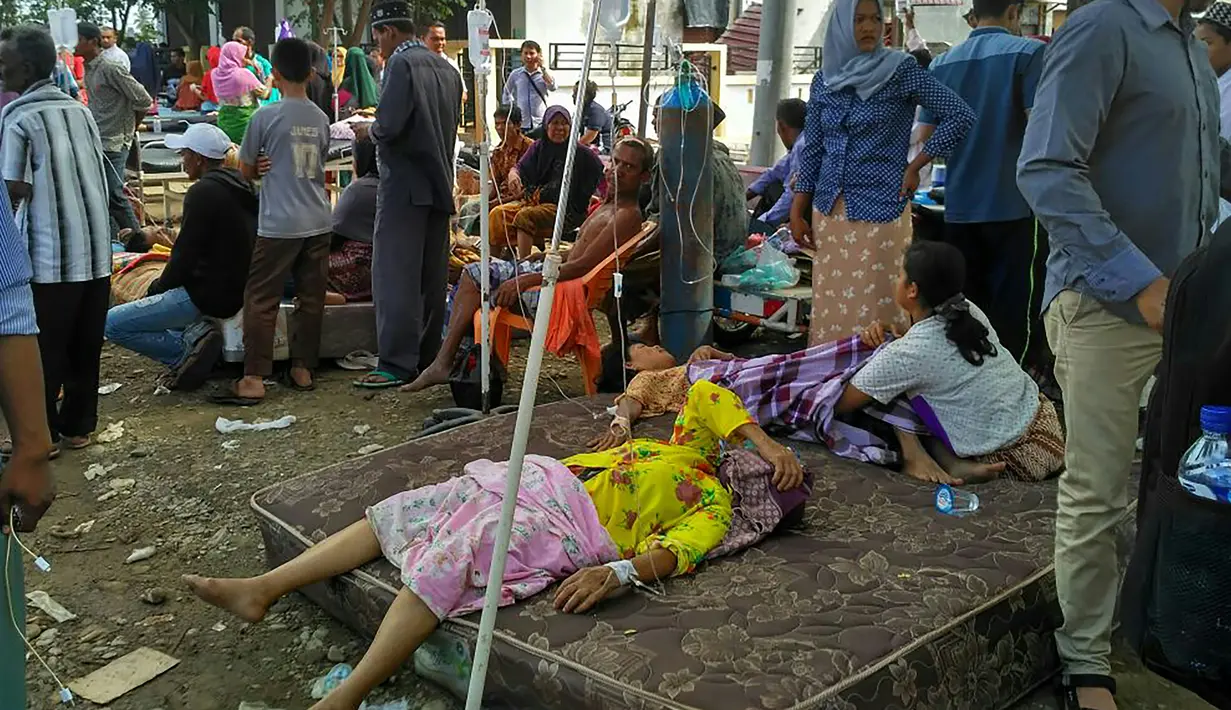 Warga saat beristiraha di luar rumahnya yang hancur akibat gempa 6,4 SR di Kabupaten Pidie Jaya, Aceh, Rabu (7/12). Seperti dirilis BMKG, gempa berkekuatan 6,4 SR mengguncang Aceh sekitar pukul 05.03 WIB. (AFP PHOTO/Chaideer Mahyuddin)