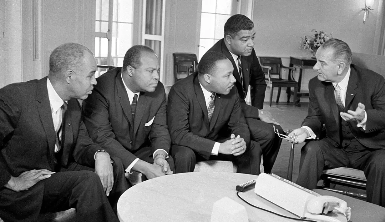 Presiden Lyndon B. Johnson (kanan) berbicara dengan Martin Luther King dan para pemimpin hak-hak sipil di Gedung Putih, Washington, 18 Januari 1964. Pembunuhan terhadap King dilakukan saat dia berdiri di balkon hotelnya. (AP Photo/File)