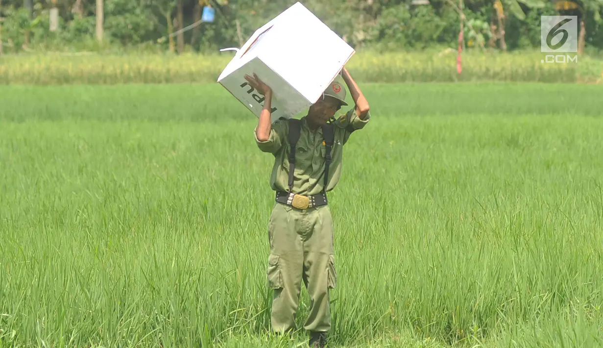 Petugas Kelompok Penyelenggara Pemungutan Suara (KPPS) membawa logistik Pemilu 2019 melintasi sawah menuju TPS di Desa Cidokom, Bogor, Selasa (16/4). Pada 17 April 2019, masyarakat dapat menunaikan haknya mencoblos, baik untuk memilih caleg maupun presiden-wakil presiden. (Merdeka.com/Arie Basuki)