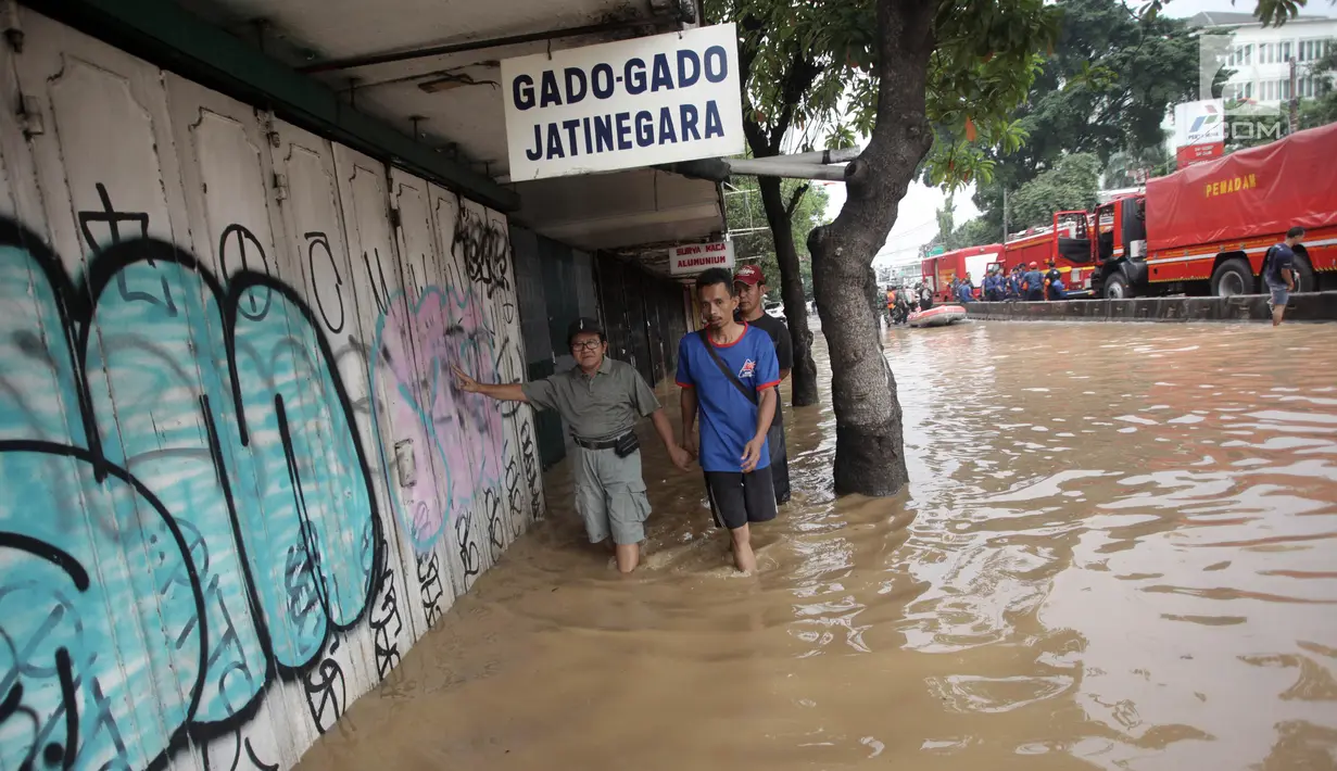 Warga berjalan melintasi banjir di Jalan Jatinegara Barat, Jakarta Timur, Selasa (6/2). Kiriman debit air dari hulu (Bogor) membuat sejumlah kawasan di bantaran Kali Ciliwung meluap(Liputan6.com/Arya Manggala)
