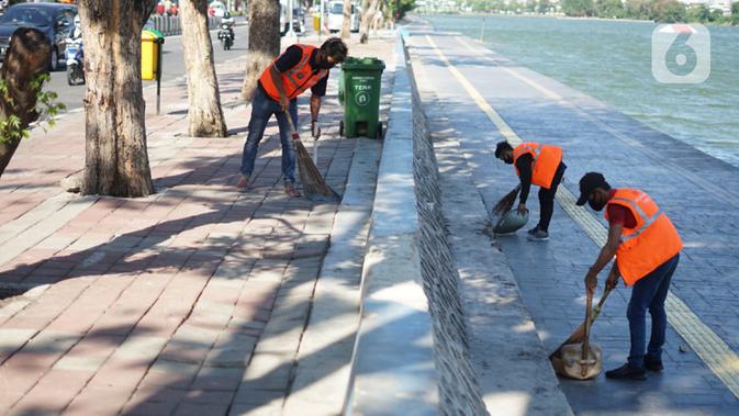 Warga pelanggar PSBB menyapu fasilitas umum saat terjaring operasi kepatuhan disiplin masker di kawasan Waduk Sunter, Jakarta, Selasa (8/9/2020). Warga yang kedapatan melanggar akan dikenakan sanksi denda Rp 250 ribu atau membersihkan fasilitas umum. (Liputan6.com/Immanuel Antonius)