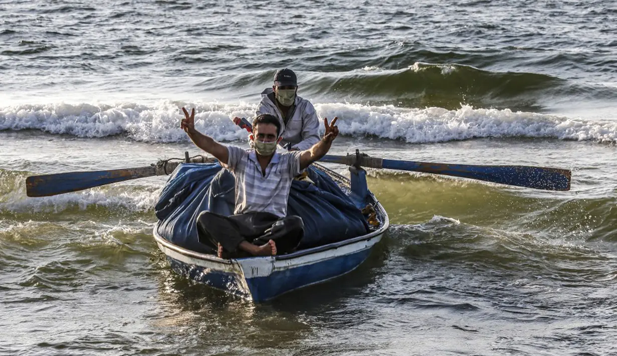 Seorang nelayan Palestina yang mengenakan masker karena pandemi virus corona COVID-19 menunjukkan isyarat kemenangan saat menangkap ikan di Laut Mediterania, Rafah, Jalur Gaza, Rabu (2/9/2020). (SAID KHATIB/AFP)