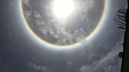 Seorang wanita ketika berada di bawah fenomena Halo Matahari yang terjadi di atas langit kota Caracas, ibu kota Venezuela, 10 Mei 2016. Fenomena langka itu dinamakan Halo Matahari yang terbentuk akibat refleksi dari kristal es. (Juan BARRETO/AFP)