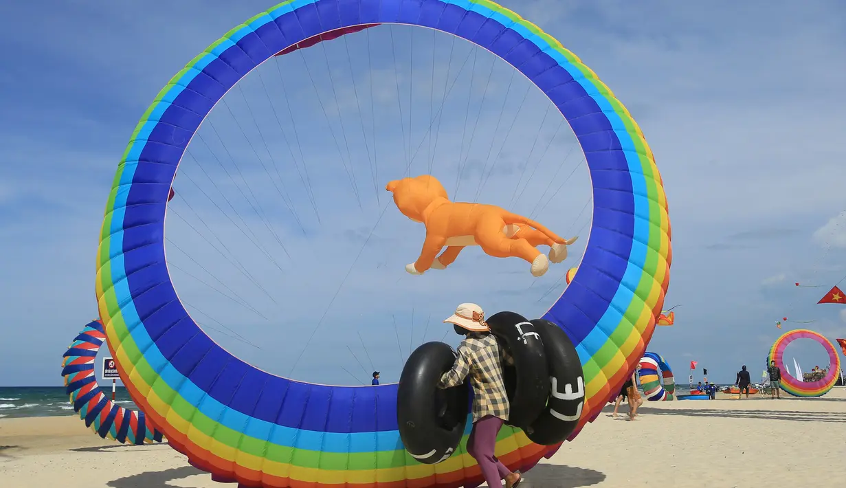 Seorang warga melintas didepan layang-layang besar yang berada di pantai Tam Thanh di Quang Nam, Vietnam (11/6). Dalam festival ini, pengrajin menunjukan keterampilan membuat, serta menerbangkan layang-layangnya. (AP Photo/Hau Dinh)