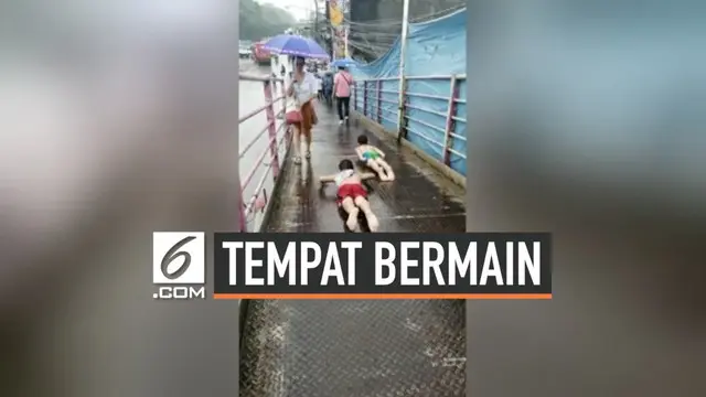Dua orang bocah Filipina jadikan jembatan penyeberangan orang menjadi tempat bermain perosotan. Mereka memenfaatkan kondisi JPO yang licin karena hujan.