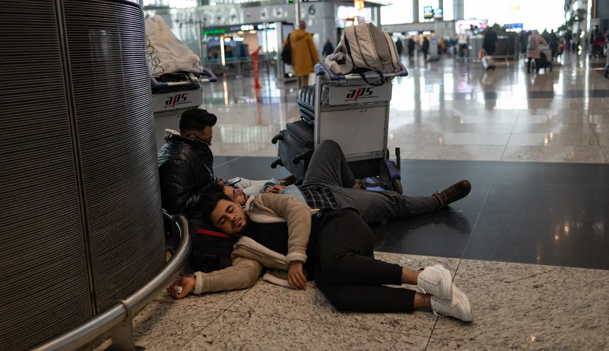 Penumpang yang terdampar menunggu di bandara Istanbul, di mana penerbangan dibatalkan karena badai salju dan hujan salju lebat, di Istanbul, Turki, pada 25 Januari 2022. Penutupan salah satu bandara tersibuk di Eropa ini akibat hantaman badai salju yang menghambat operasional. (Yasin AKGUL/AFP)