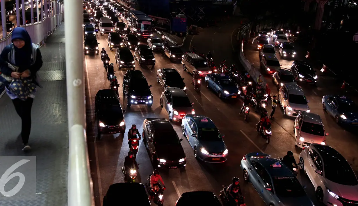 Pejalan kaki melintas di halte busway dengan latar kemacetan kota Jakarta di kawasan Semanggi, Jakarta, Selasa (18/10). Jakarta dikenal sebagai salah satu kota yang memiliki kemacetan lalu lintas terburuk di dunia. (Liputan6.com/Johan Tallo)