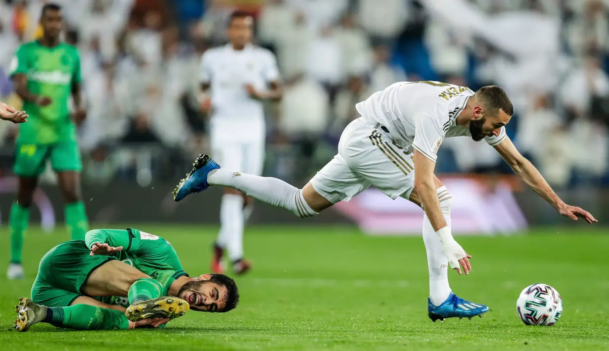 Striker Real Madrid, Karim Benzema melewati pemain Real Sociedad, Mikel Merino selama laga perempat final Copa del Rey di Santiago Bernabeu, Kamis (6/2/2020). Real Madrid gagal melaju ke semifinal Copa del Rey setelah dibungkam Real Sociedad dengan skor 3-4. (AP Photo/Manu Fernandez)