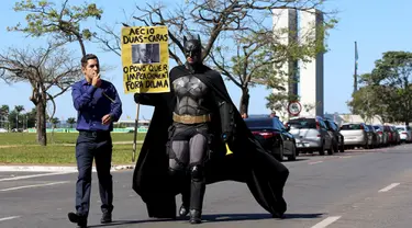 Seorang aktivis mengenakan kostum superhero Batman turun ke jalan memprotes Presiden Brasil Dilma Rousseff di Gedung Kongres Nasional, Brasil (27/5/2015). Aktivis ini menuntut keadilan terkait kebijakan pemotongan anggaran. (REUTERS/Adriano Machado)