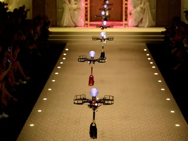Deretan pesawat tanpa awak (drone) membawa koleksi tas tangan Dolce & Gabbana pada Milan Fashion Week 2018, Minggu (25/). Drone ini keluar dari belakang panggung, lalu terbang sambil membawa koleksi tas yang harganya terbilang selangit (Miguel MEDINA/AFP)
