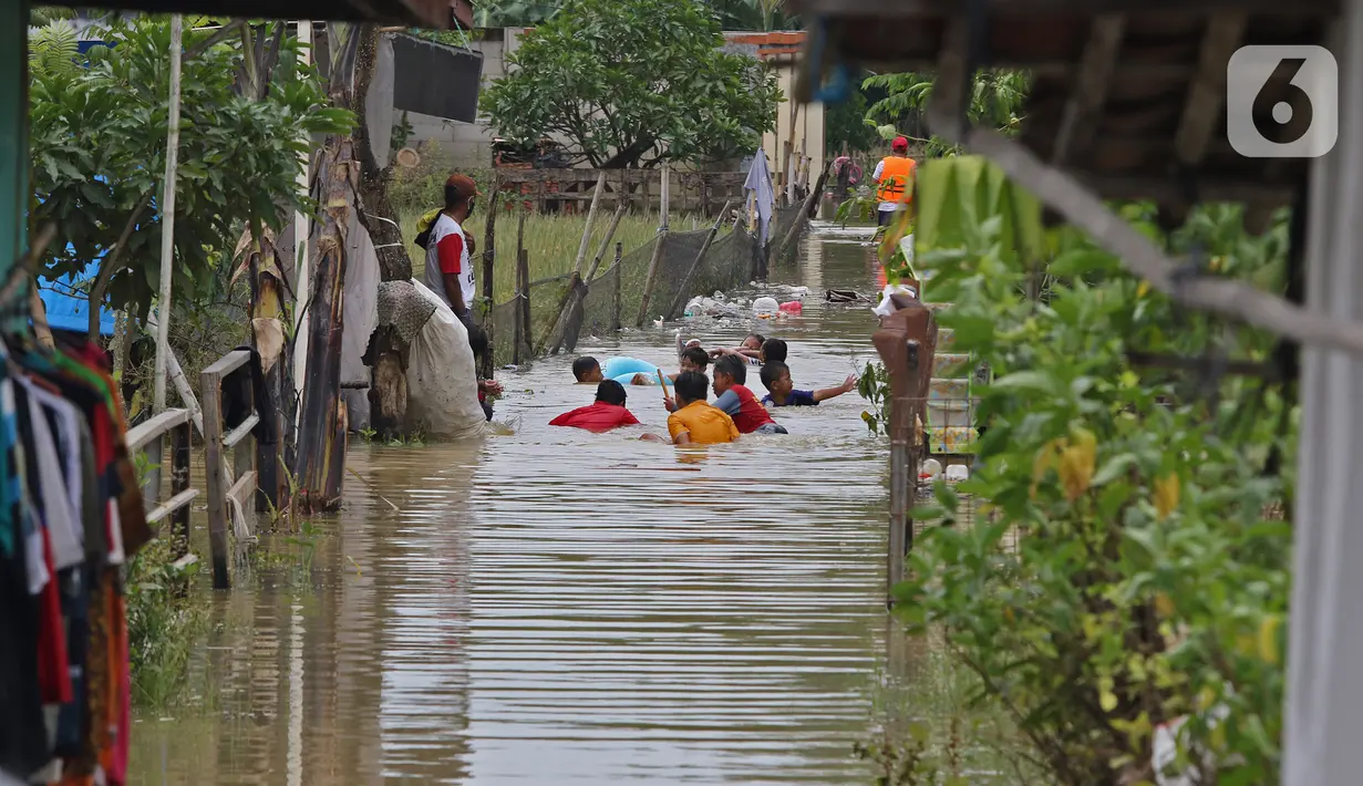 Anak-anak bermain saat banjir merendam Desa Karangligar, Kecamatan Telukjambe Barat, Karawang, Jawa Barat, Kamis (10/2/2021). Banjir di Desa Karangligar akibat meluapnya sungai Citarum dan Cibeet membuat ratusan rumah terendam banjir dan ratusan hektar sawah. (Liputan6.com/Herman Zakharia)