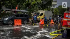 Sejumlah personil pemadam kebakaran membersihkan tumpah oli yang terjadi di Jalan Veteran depan Gedung Krida Bakti, Jakarta, Kamis (16/1/2020). Petugas damkar  melakukan pembersihan dengan cairan deterjen maupun campuran khusus agar jalan tersebut tidak lagi licin. (Liputan6.com/Faizal Fanani)