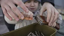 Seorang anak kecil mengeluarkan amunisi selama pelatihan perang dasar untuk warga sipil, oleh Unit Pasukan Khusus Azov, dari Garda Nasional Ukraina, di Mariupol, wilayah Donetsk, Minggu (13/2/2022). Mereka disiapkan untuk bisa bertahan di tengah kekhawatiran akan invasi Rusia (AP Photo/Vadim Ghirda)