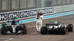 Pebalap Mercedes, Lewis Hamilton (depan) dan rekannya Valtteri Bottas merayakan keberhasilan masuk finis pada balapan F1 Abu Dhabi di Yas Marina circuit , (26/11/2017). Bottas finis pertama. (AFP/Karim Sahib)