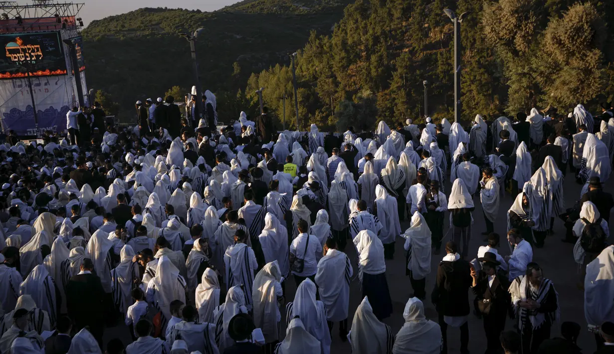 Orang-orang Yahudi Ultra Ortodoks yang ditutupi selendang berdoa saat perayaan liburan Lag BaOmer di situs makam tradisional Rabbi Shimon Bar Yochai di Gunung Meron, Israel, Kamis (19/5/2022). Orang Israel menyalakan api unggun selama perayaan Lag BaOmer untuk memperingati berakhirnya wabah yang dikatakan telah memusnahkan orang Yahudi di zaman Romawi. (AP Photo/Ariel Schalit)