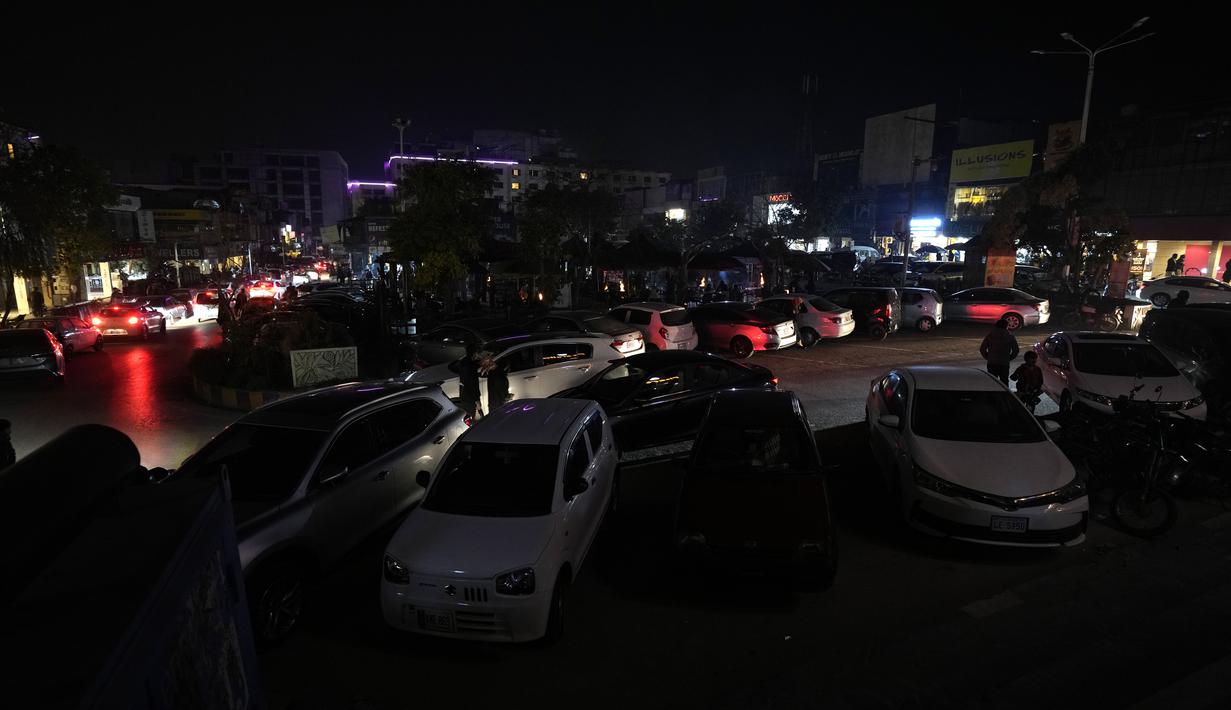 Sebuah mobil melaju di pasar, di mana beberapa pemilik toko menggunakan generator untuk listrik selama gangguan listrik nasional, di Islamabad, Pakistan, Senin, 23 Januari 2023. Kementerian Energi mengemukakan bahwa gangguan itu dimulai setelah pukul 07.00 waktu setempat dan pekerjaan sedang berlangsung untuk menghidupkan kembali sistem. (AP Photo/K.M. Chaudary)
