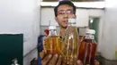 Hamidi memegang tiga botol berisi bahan bakar yang berasal dari pembakaran sampah plastik di bengkel kerjanya dekat TPA Rawa Kucing, Tangerang, (17/3). Hamidi membuat inovatif yang mengubah sampah plastik menjadi bahan bakar. (REUTERS / Beawiharta)