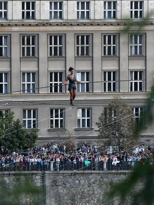Penonton menyaksikan aksi akrobat perempuan, Tatiana Mosio Bongonga, meniti tali melintas di atas sungai Vltava di ibu kota Ceko, Praha, Rabu (14/8/2019). Tatiana  berjalan di ketinggian 35 meter tanpa menggunakan alat pengaman sama sekali. (Michal Cizek / AFP)