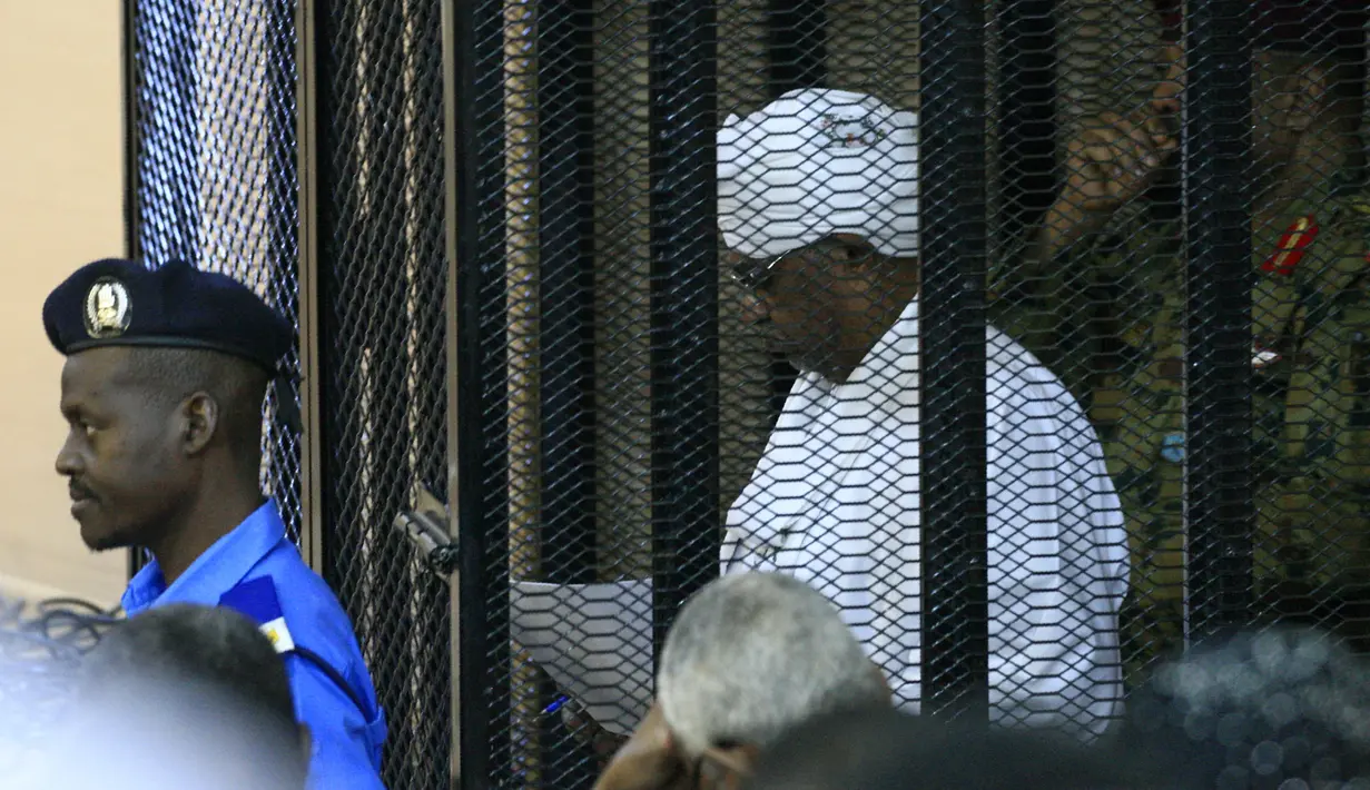 Presiden terguling Sudan, Omar al-Bashir ditempatkan di kandang terdakwa selama menjalani persidangan atas dakwaan korupsi di pengadilan di Khartoum, Senin (19/8/2019). Bashir  didakwa dengan tuduhan korupsi, kepemilikan mata uang asing dan menerima gratifikasi. (Ebrahim HAMID / AFP)